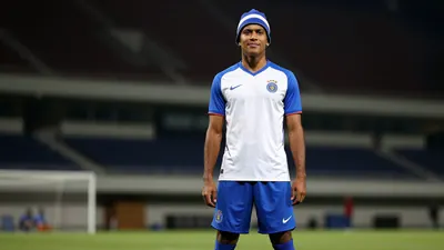 A 33-year-old, dark-skinned, athletic, waist-up, head-and-shoulders shot of a player in a white jersey with blue sleeves...