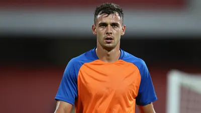 Mid-30s athletic male Oldham player, focused and sweat-glazed, torso turned slightly toward camera, wearing a plain...