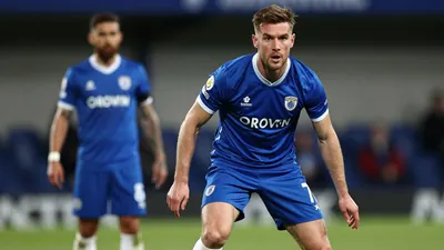 A tight action crop of an Oldham Athletic player in a focused, intense moment, and photorealistic skin and fabric...