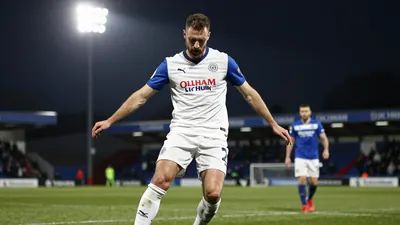 A photorealistic image of an anonymous Oldham Athletic left-back, aged 25-30, in a white jersey with blue sleeves and a...