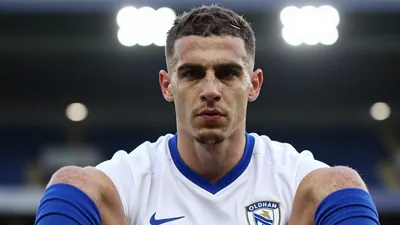 A photorealistic image of an anonymous Oldham Athletic player in a white home kit with a blue collar and blue socks...