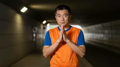 A 35-year-old digital strategist, dressed in a plain orange jersey with blue sleeves and a blue collar, made from a...