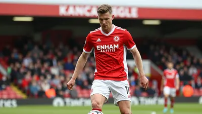 A photorealistic image of an Oldham Athletic player, aged 25-30, in a red and white striped jersey, with a white collar...