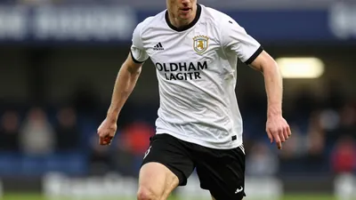 A photorealistic image of an anonymous Oldham Athletic player, aged 18-22, with a clean white jersey and black shorts...