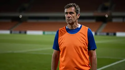A 35-year-old, 5'9" assistant coach with a rugged build, stands intensely on the Boundary Park pitchside grass, his face...
